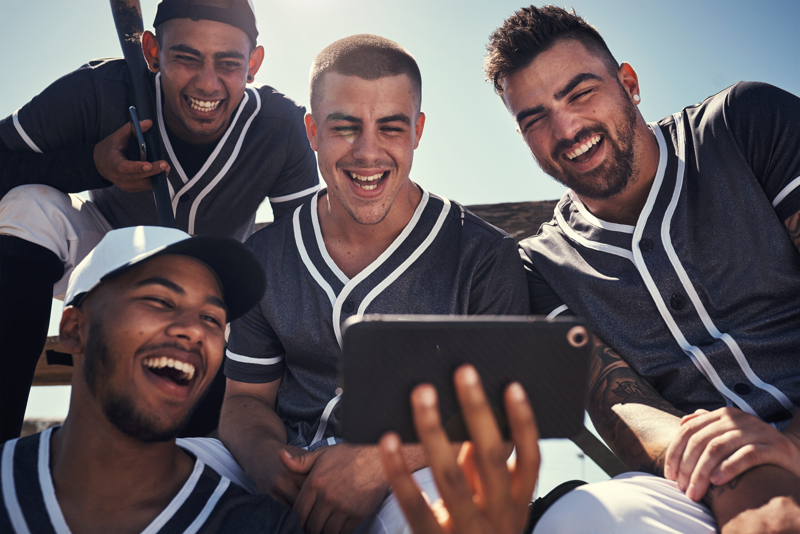 Shot of a group of young men using a smartphone after playing a baseball game.
